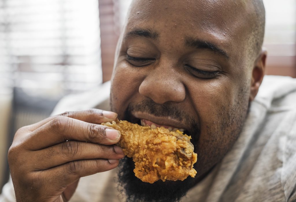 Man eating a piece of fried chicken